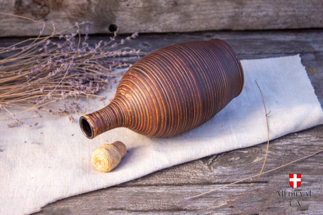 Milk fired clay bottle lying on its side with the cork removed, showing the ribbed throw lines