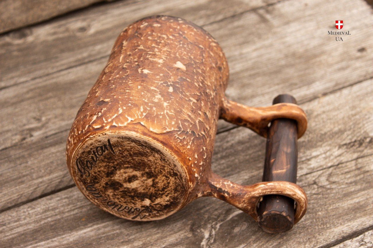 Base of the handmade milk-fired tankard tilted to show the maker's handwritten signature on the bottom