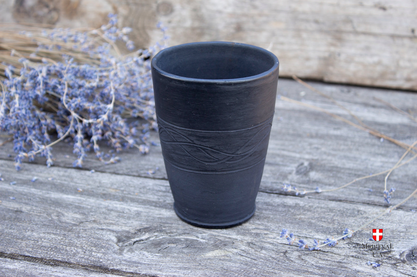 Black smoke-fired pottery goblet on a wooden table, front view