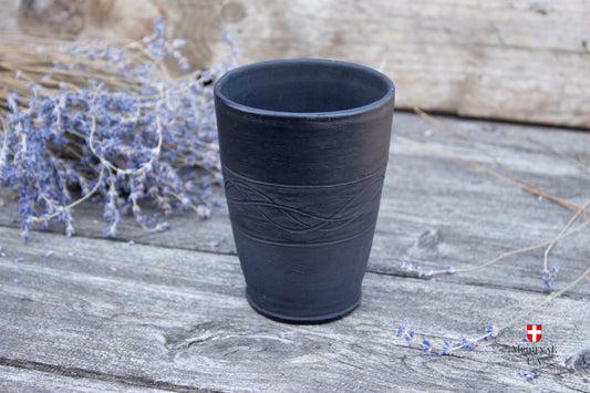 Black smoke-fired pottery goblet on a wooden table, front view