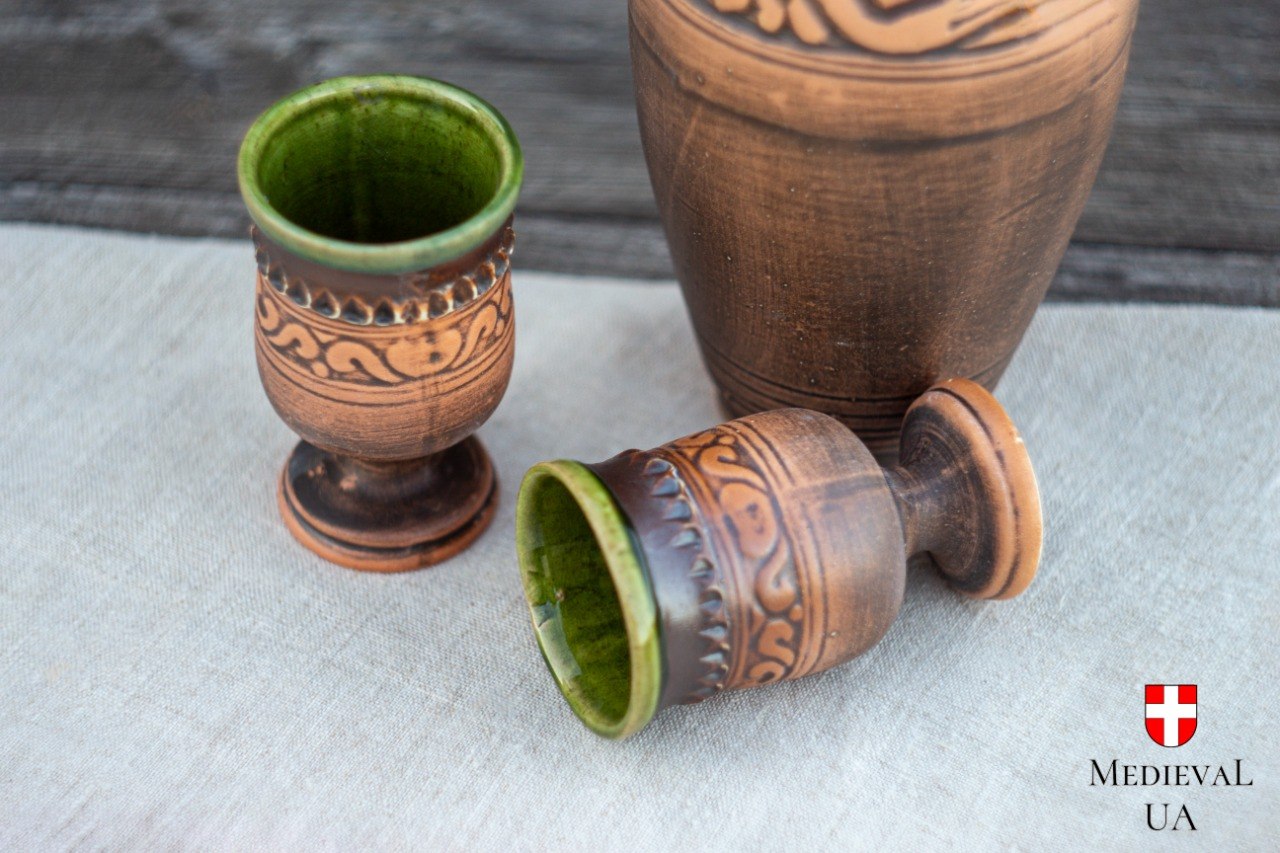 Close-up of two folk-style ceramic goblets revealing food-safe deep-green glazed interior