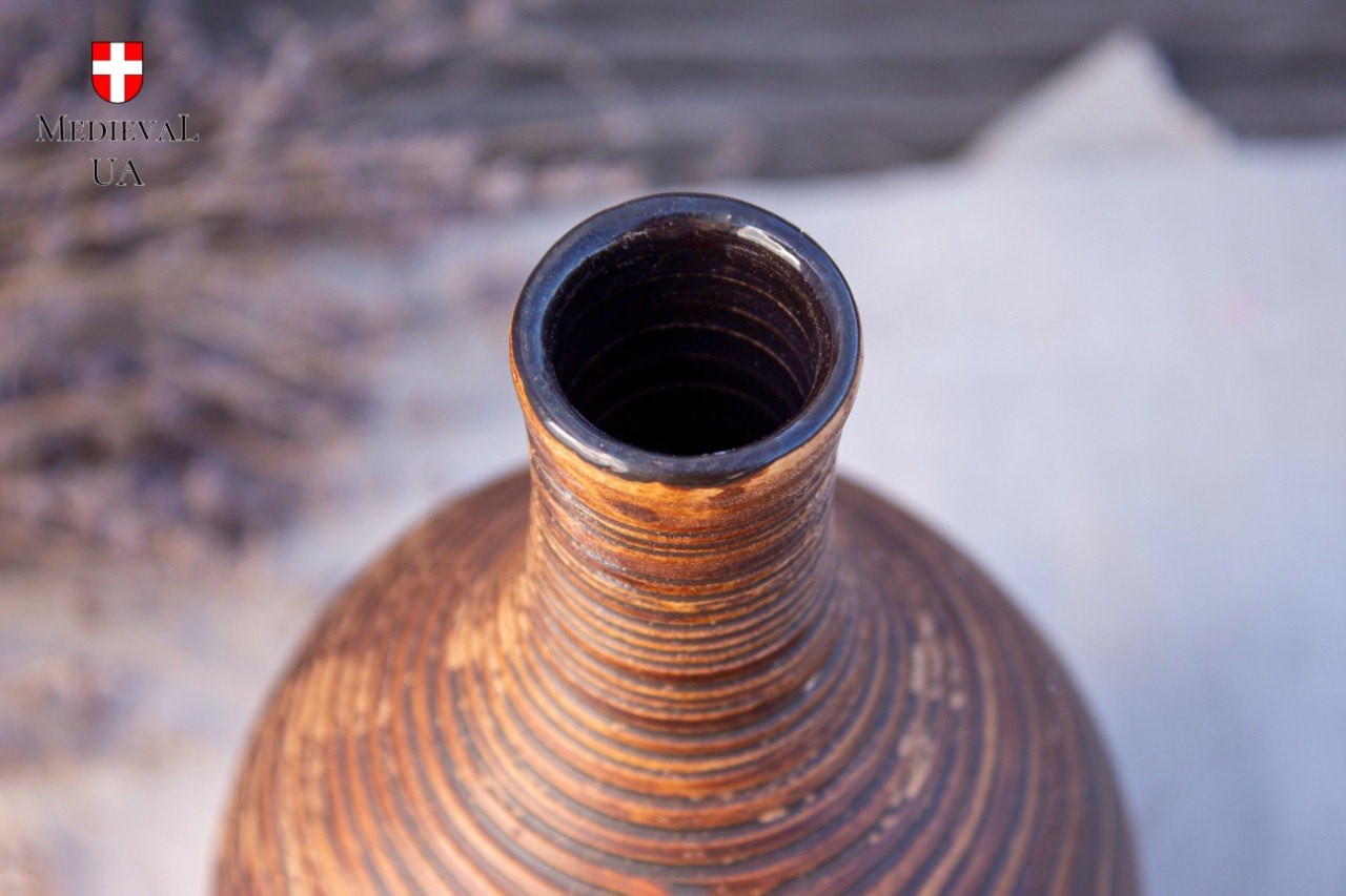 Detail of the narrow ribbed neck of a clay bottle with its dark glazed interior visible