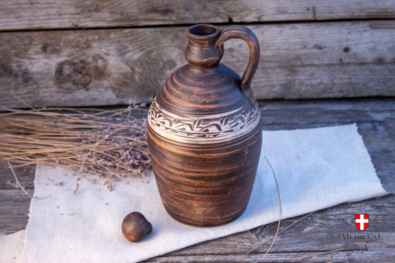 Unglazed red clay bottle with its round ceramic stopper set beside it