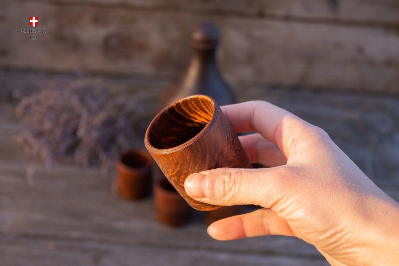 Handmade red clay cup held in the hand for serving mead