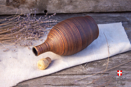 Milk fired clay bottle lying on its side with the cork removed, showing the ribbed throw lines