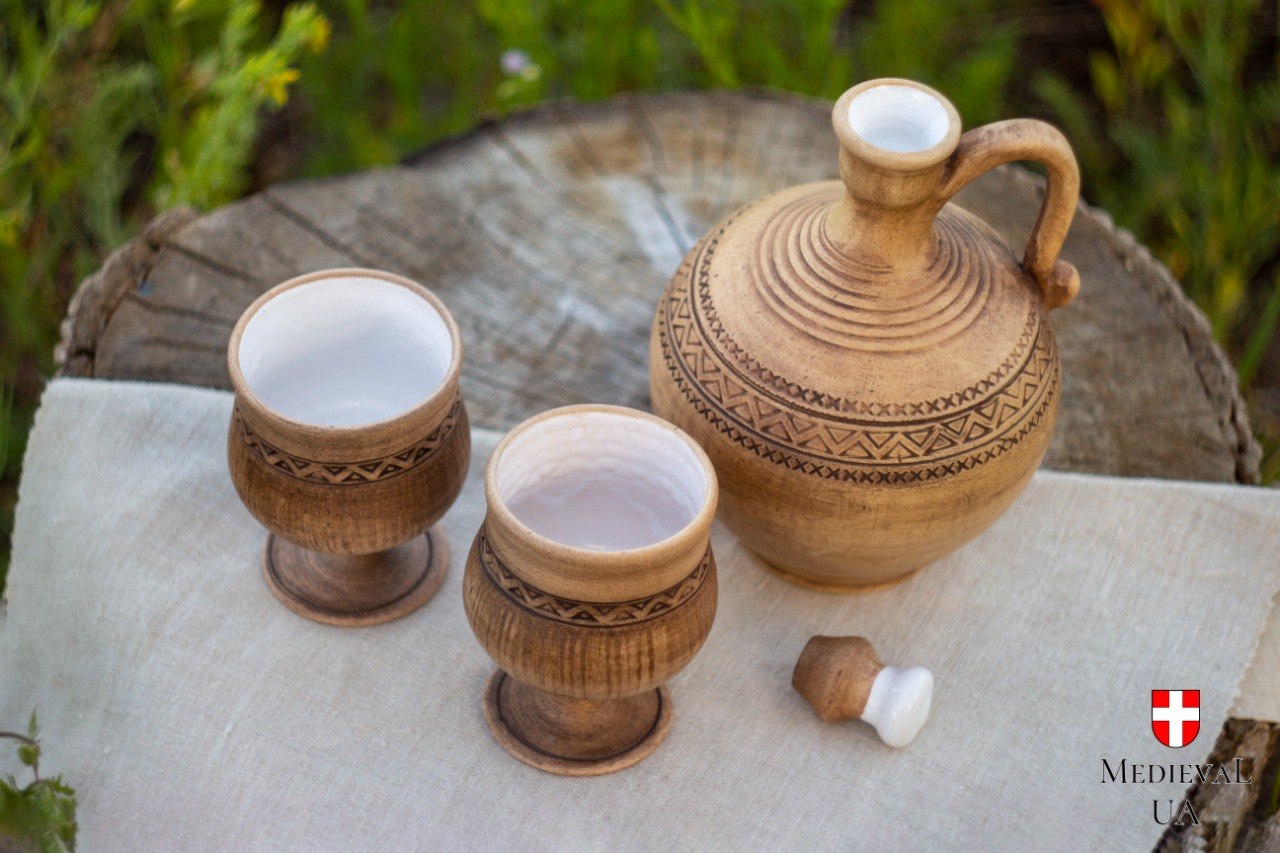 Cottagecore wine set with a round ceramic carafe and two matching goblets on a wooden stump