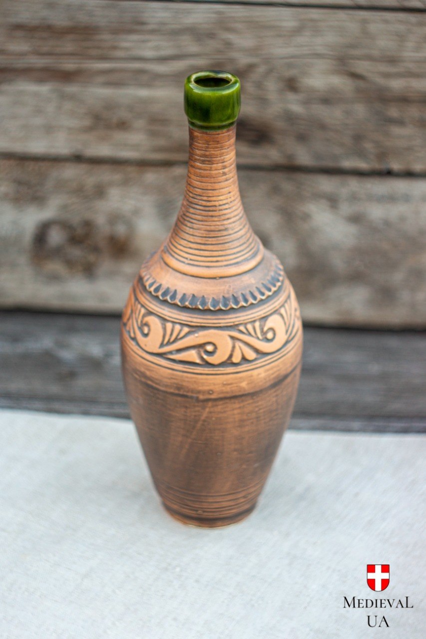 Handmade ceramic mead and wine bottle with folk-medieval relief and green glazed top, standing upright