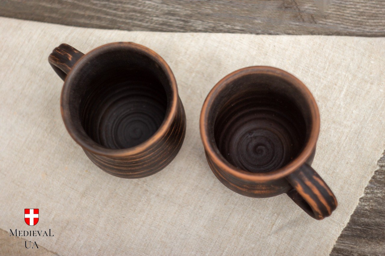 Top view of two matching handmade clay mugs revealing spiral wheel-thrown interiors