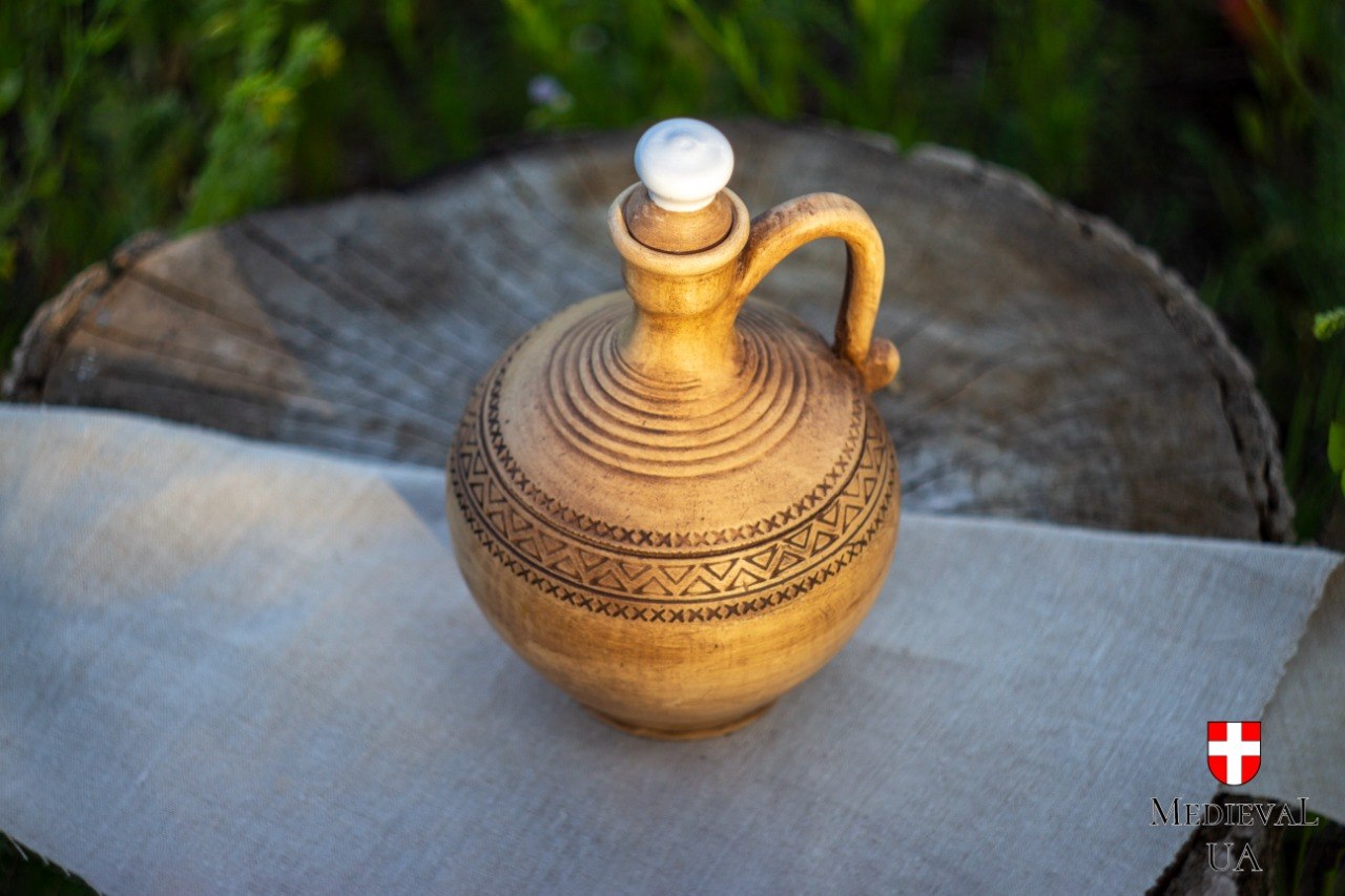 Top-angle view of a handmade pottery jug showing spiral rings and a carved decorative band