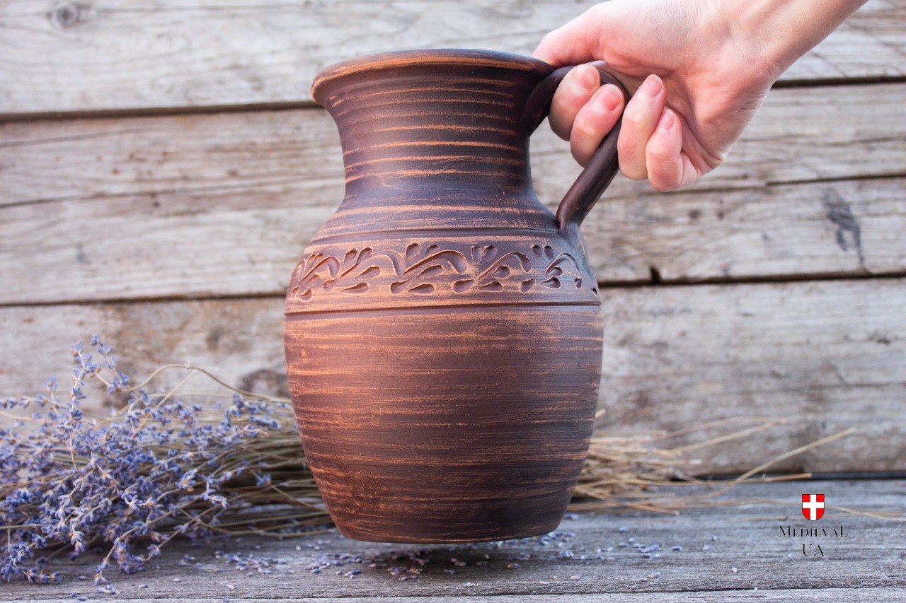 Handmade ceramic wine pitcher held by the handle, side view