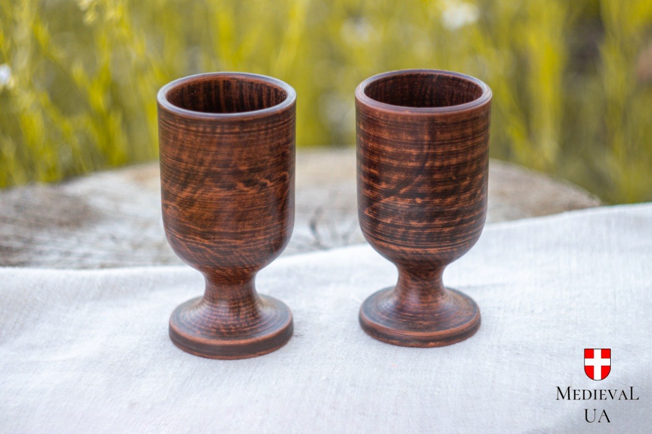 Pair of matching red clay footed goblets side by side, deep terracotta with wood-grain firing