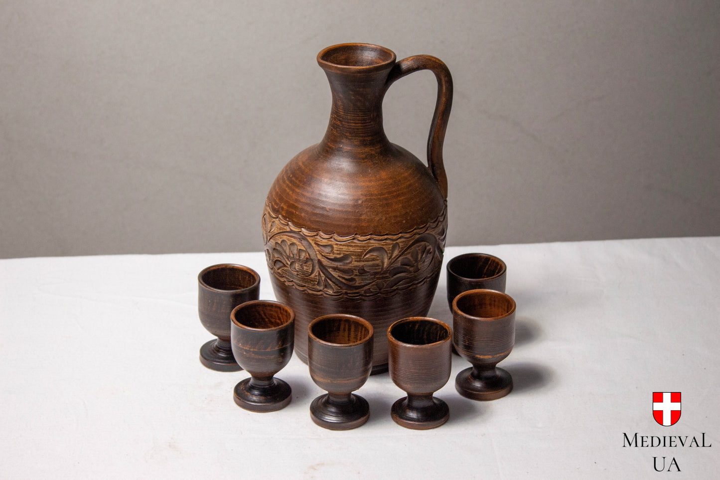 Medieval wine jug set with carved clay jug and six footed cups
