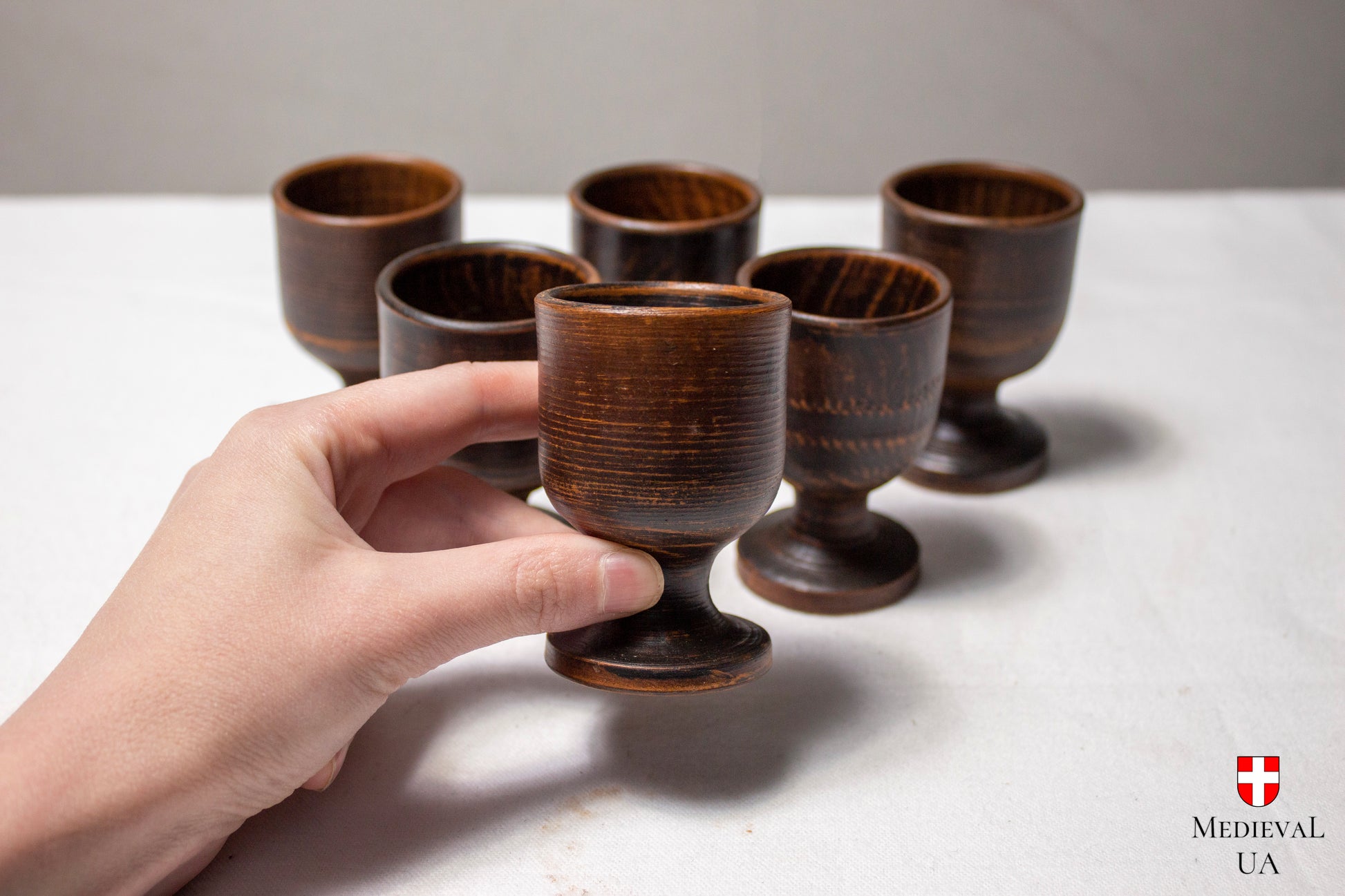 Handmade clay cordial cup held by the stem above five more
