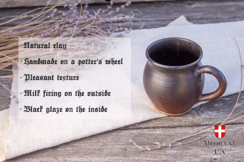 Dark milk-fired tea mug on linen with a feature list: natural clay, wheel-thrown, milk firing, black glaze