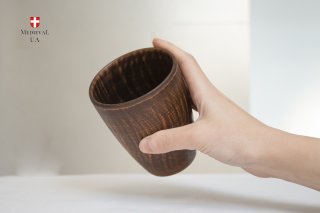 Hand holding a rustic unglazed clay drinking cup