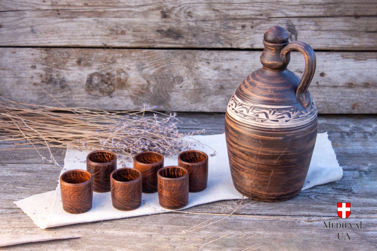 Medieval drinking set with clay flagon and six pottery cups on linen cloth