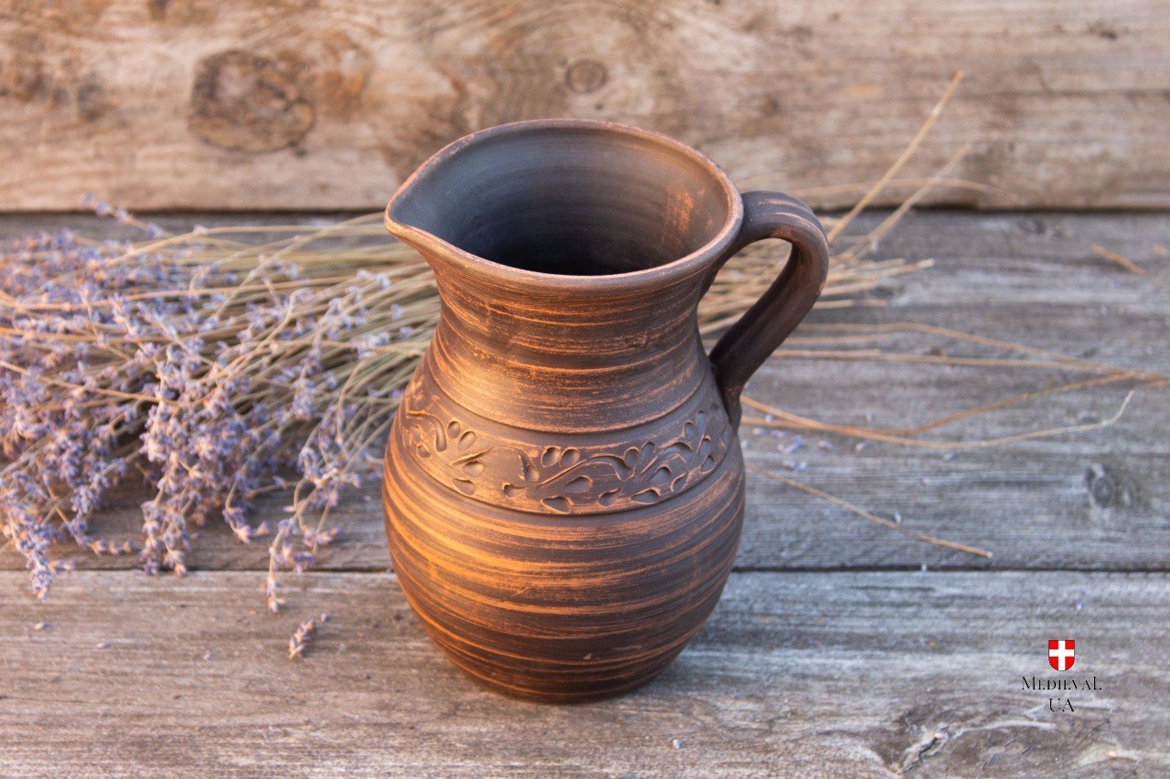 Brown medieval clay jug with carved leaf pattern and handle