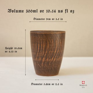 Handmade medieval red clay tumbler on a wooden table, front view, size