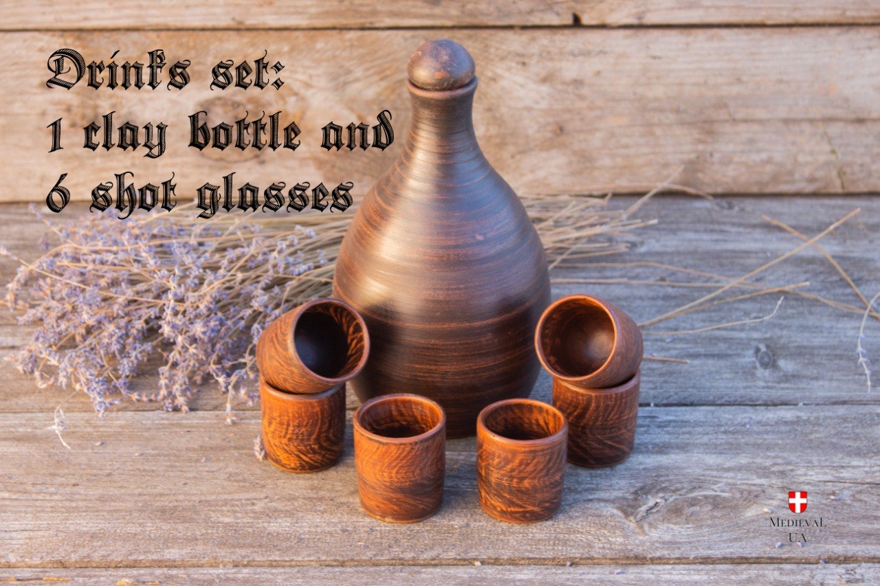 Rustic clay bottle with six shot cups arranged on weathered wood