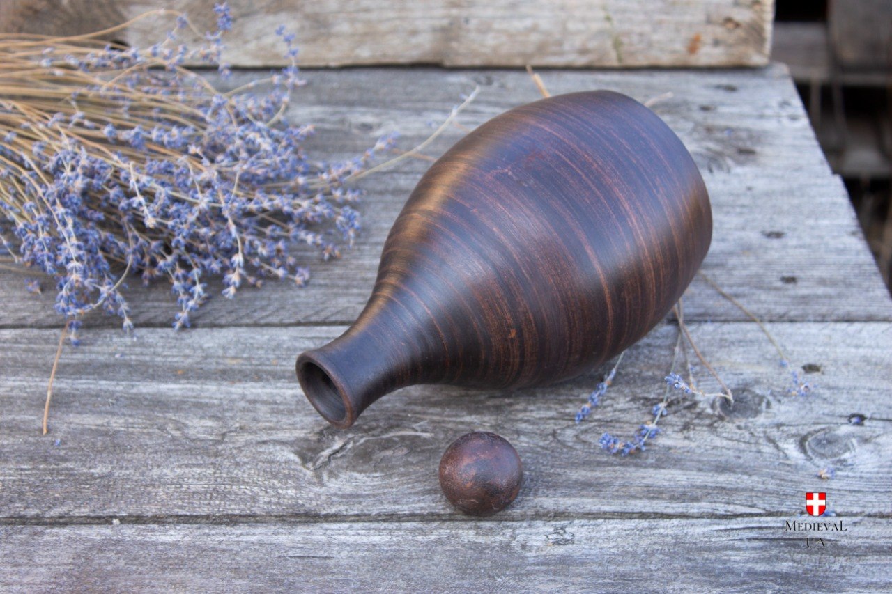 Plain milk-fired clay mead bottle lying beside its round stopper