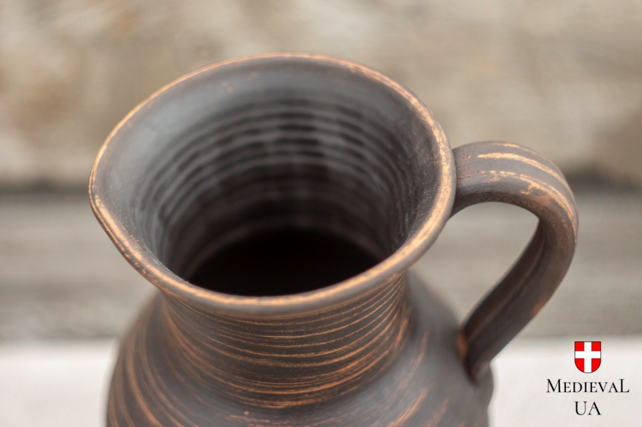 Close-up of red clay jug mouth and handle, revealing ridged wheel-thrown interior