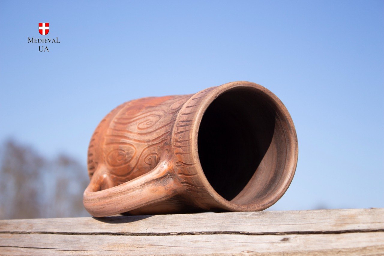 Red clay tankard tipped on its side showing the wide rim and unglazed interior