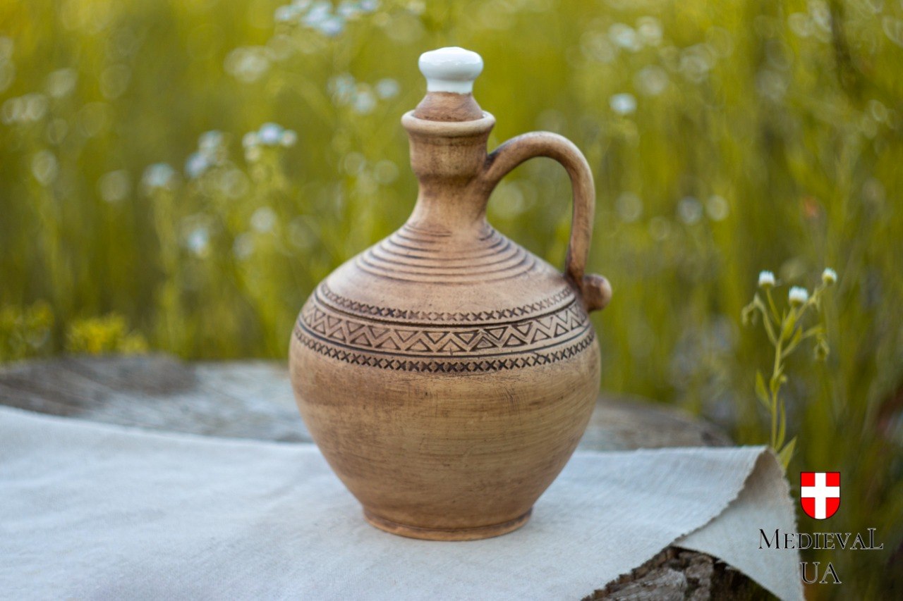 Rustic ceramic wine carafe with a looped handle and ceramic stopper set among wildflowers