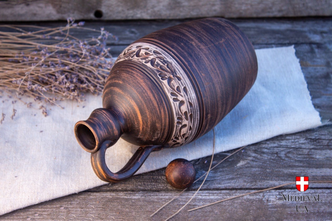 Clay flagon on its side revealing the narrow pouring neck and carved band