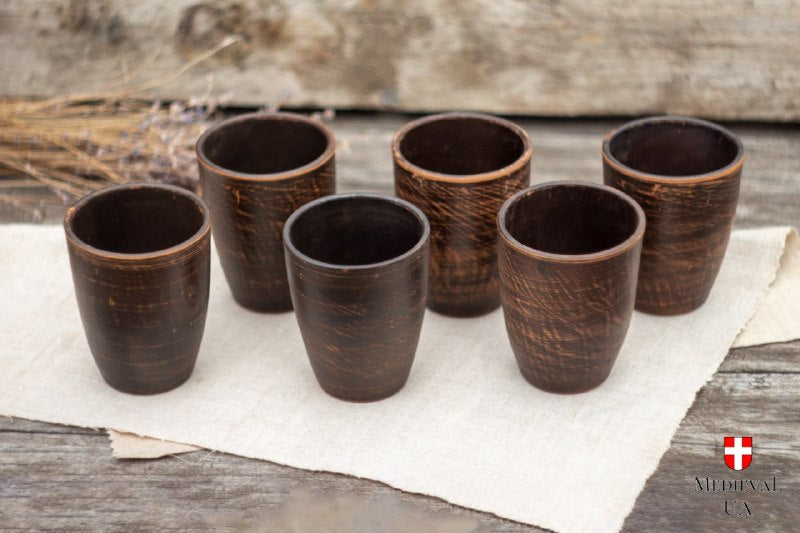 Set of six wheel thrown clay cups arranged together on natural linen cloth