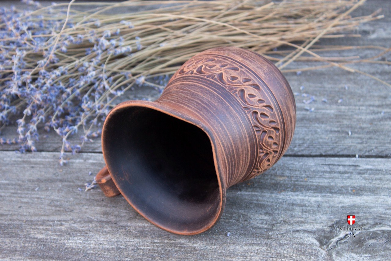Small clay pitcher lying down showing interior and carved belly