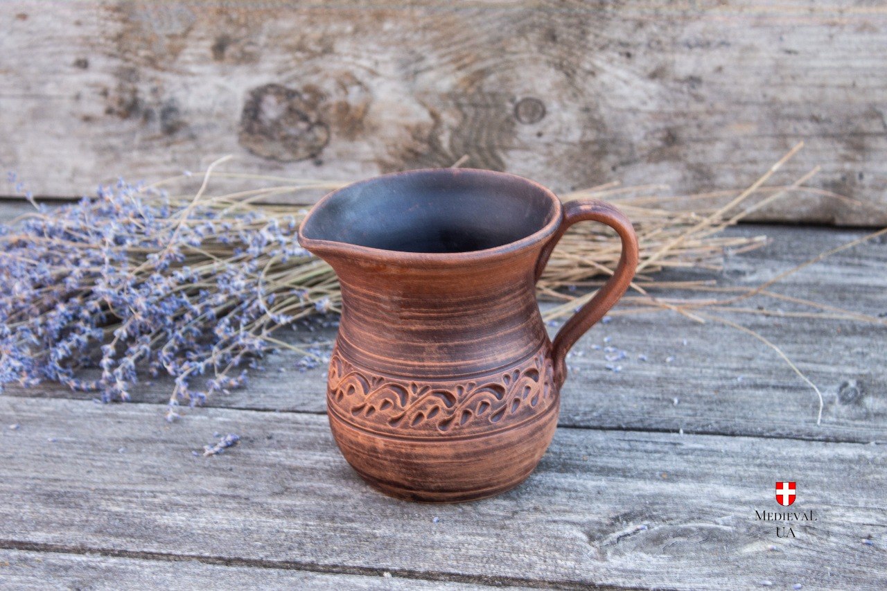 Small clay pitcher lying down showing interior and carved belly