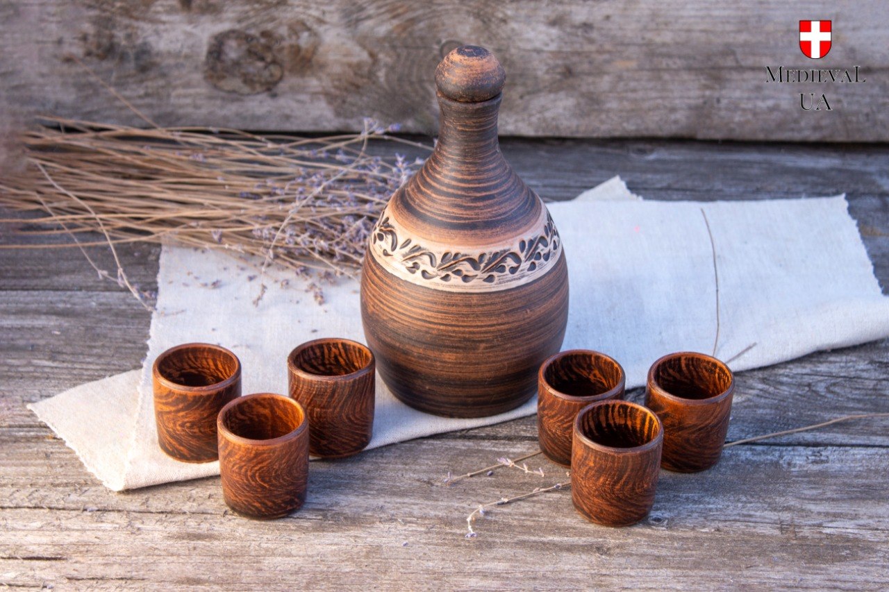 Viking mead set with carved clay bottle and six matching cups on linen