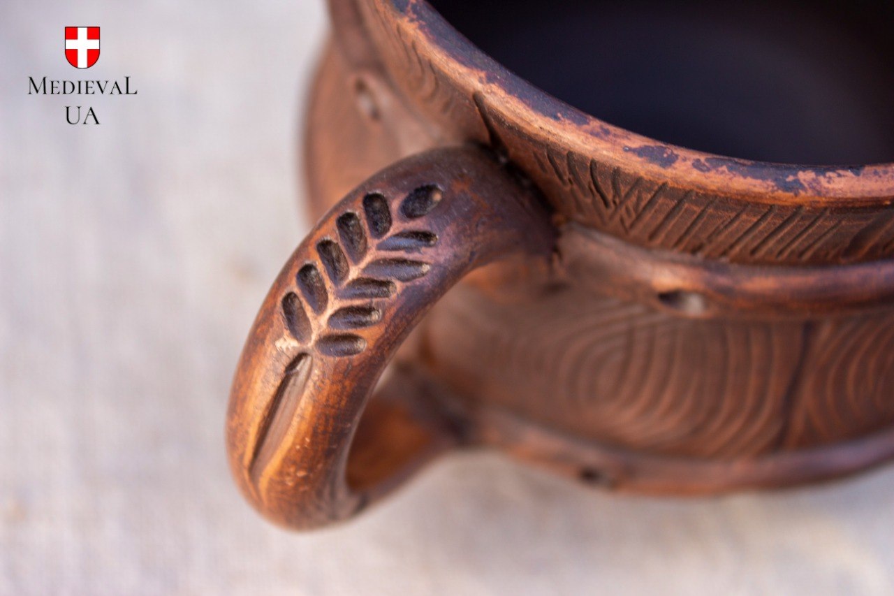 Close-up of the carved leaf motif on the handle of the handmade milk-fired clay mug