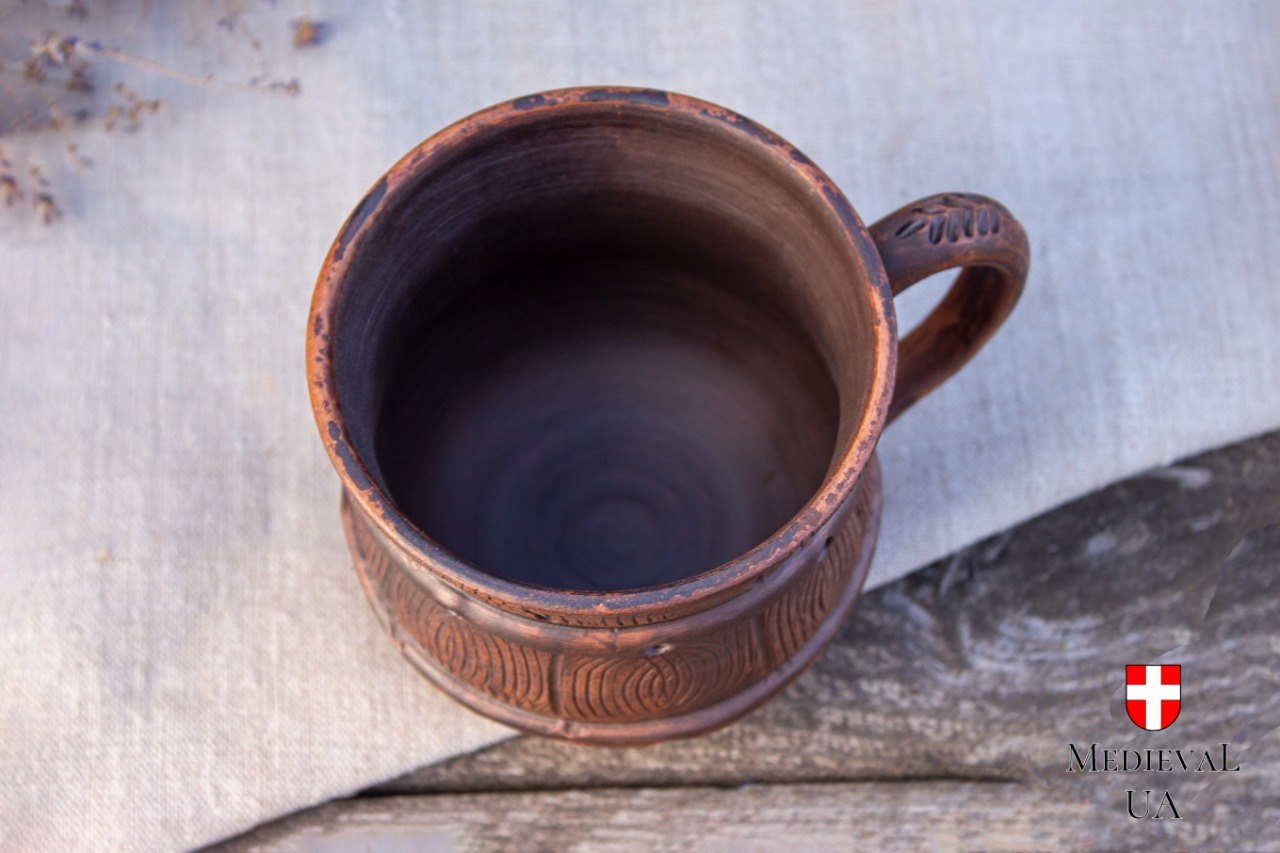 Top view of the handmade red clay mug showing the dark wheel-thrown interior and carved rim
